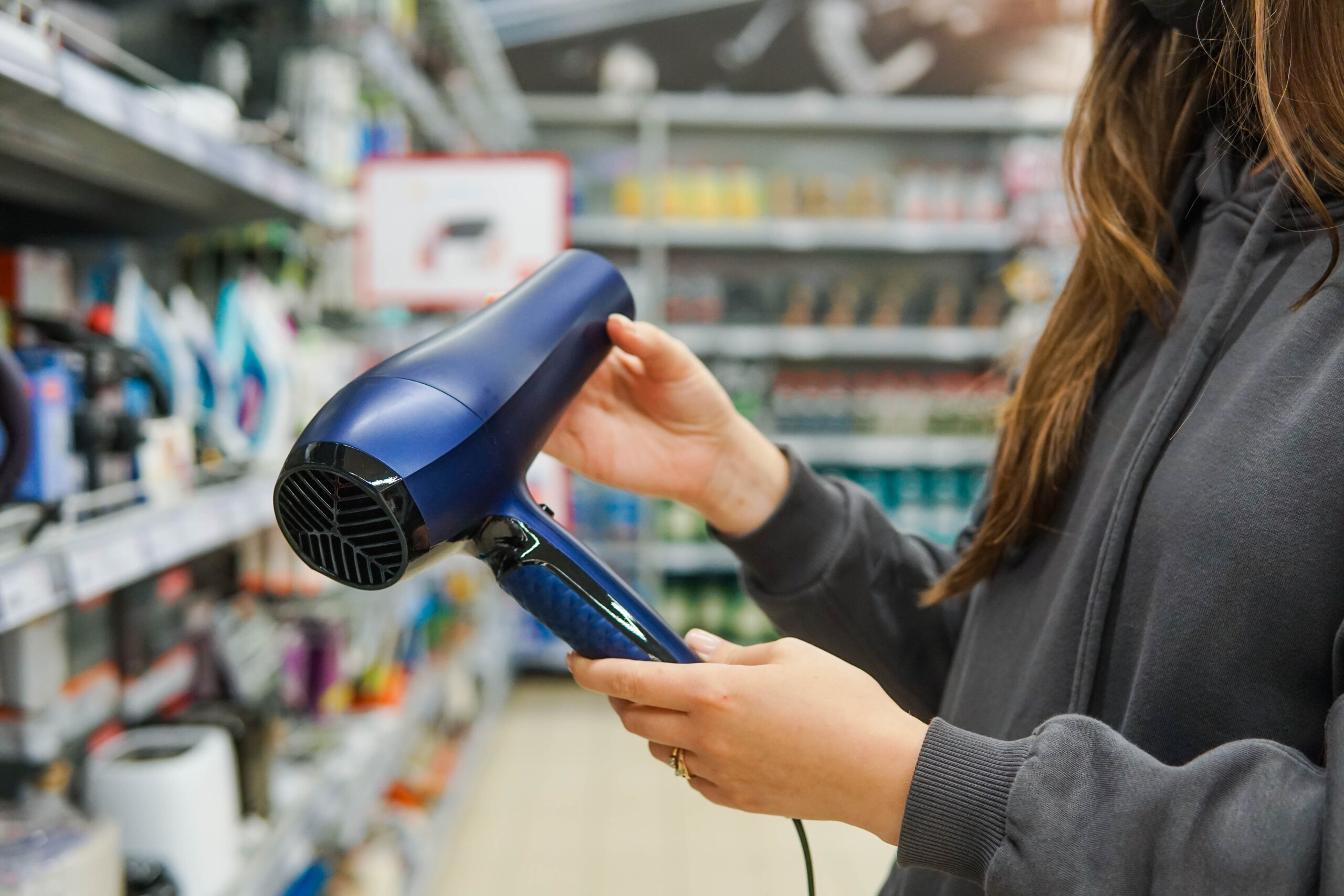 Woman customer choosing a hairdryer at store, close up